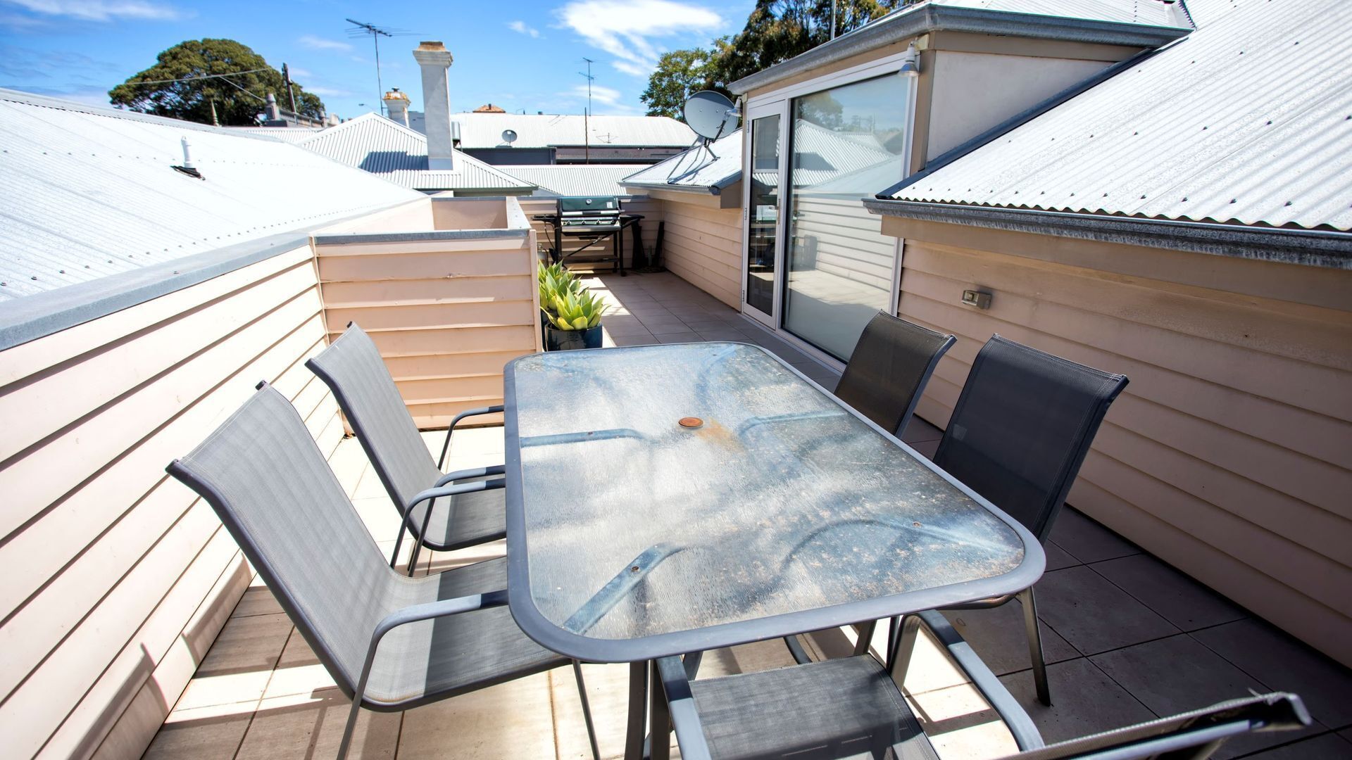 A patio with a table and chairs, a small satellite dish, and a sliding glass door.
