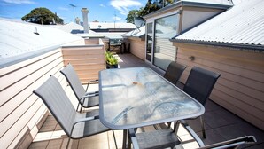 En terrasse med et bord og stole, en lille satellitmodtager og en skydedør af glas.