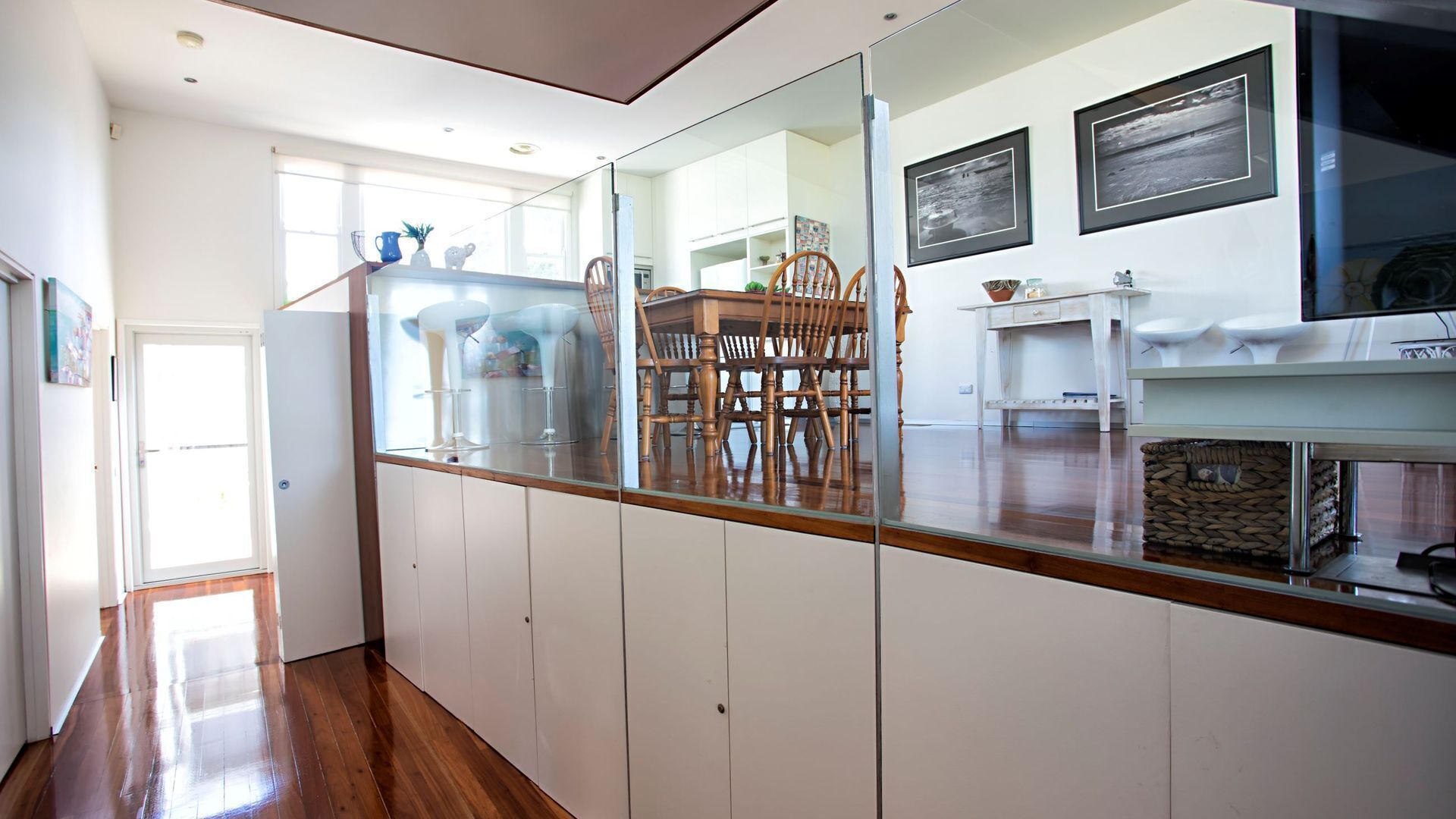 A modern kitchen with wooden chairs, a dining table, and a glass partition.