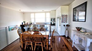 A modern kitchen with wooden chairs, a dining table, and a large window.
