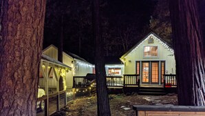 A cabin with a deck and string lights, surrounded by trees. - Dandelion's Lair, a 3 bedroom, 2.5 bathroom cabin in Twain Harte! (Twain Harte)
