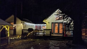 A house with a porch, a covered area, and a fenced yard at night. - Dandelion's Lair, a 3 bedroom, 2.5 bathroom cabin in Twain Harte! (Twain Harte)