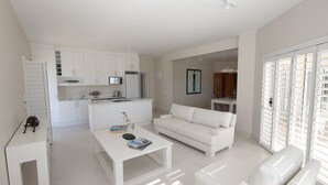 A modern, white-themed living space with a kitchen, a white sofa, and a dining area. - Stella Maris (Plettenberg Bay)