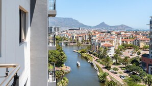 Een hoog gebouw met uitzicht op een rivier, met een stadsbeeld en bergen op de achtergrond.