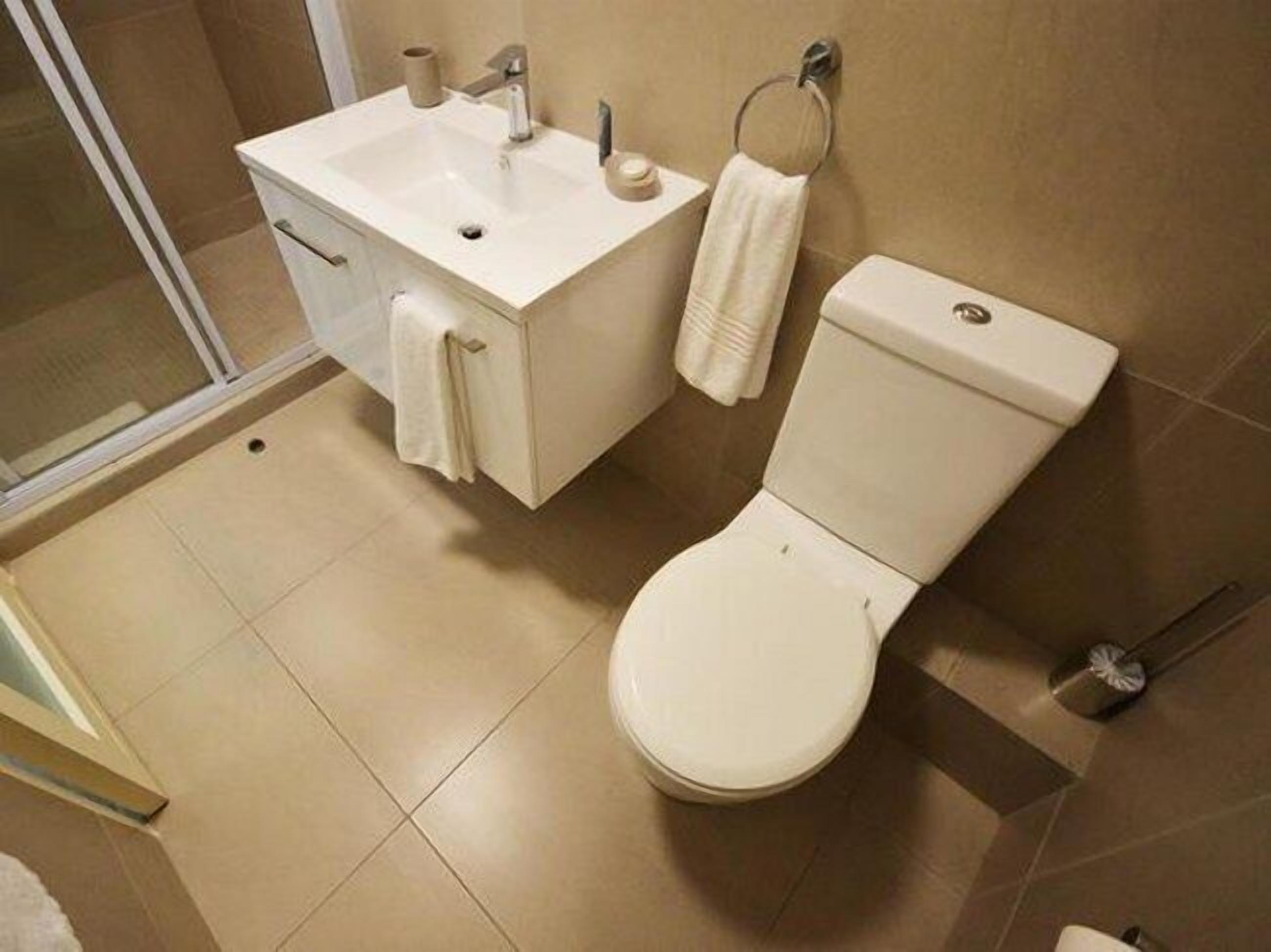 A bathroom with a white sink, toilet, and a towel rack.