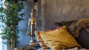 Una sala de estar acogedora con un sofá, una estatua decorativa de Buda, una planta en maceta y velas sobre una bandeja.