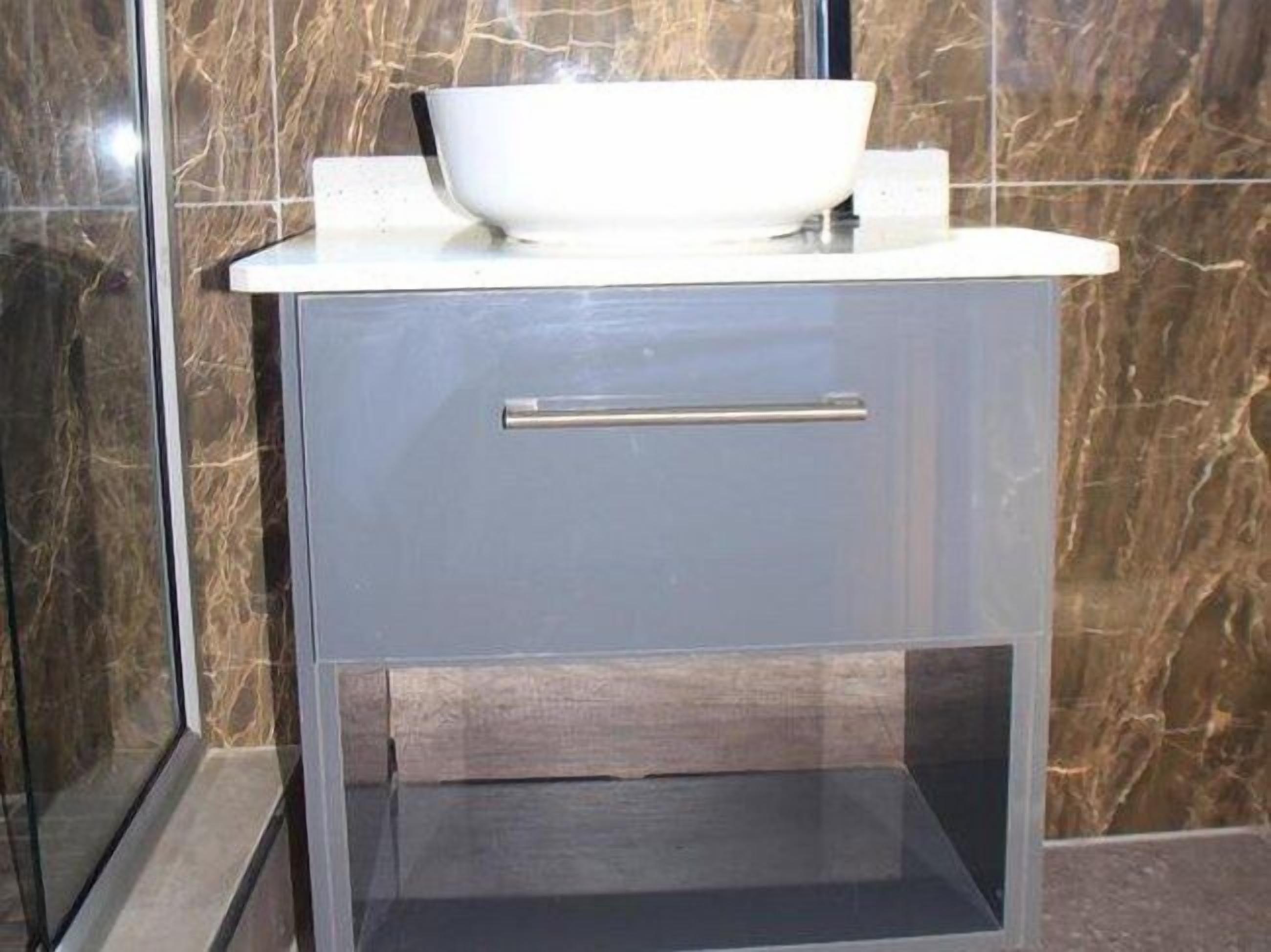Un baño con lavamanos blanco, un cajón y salpicadero de mármol.