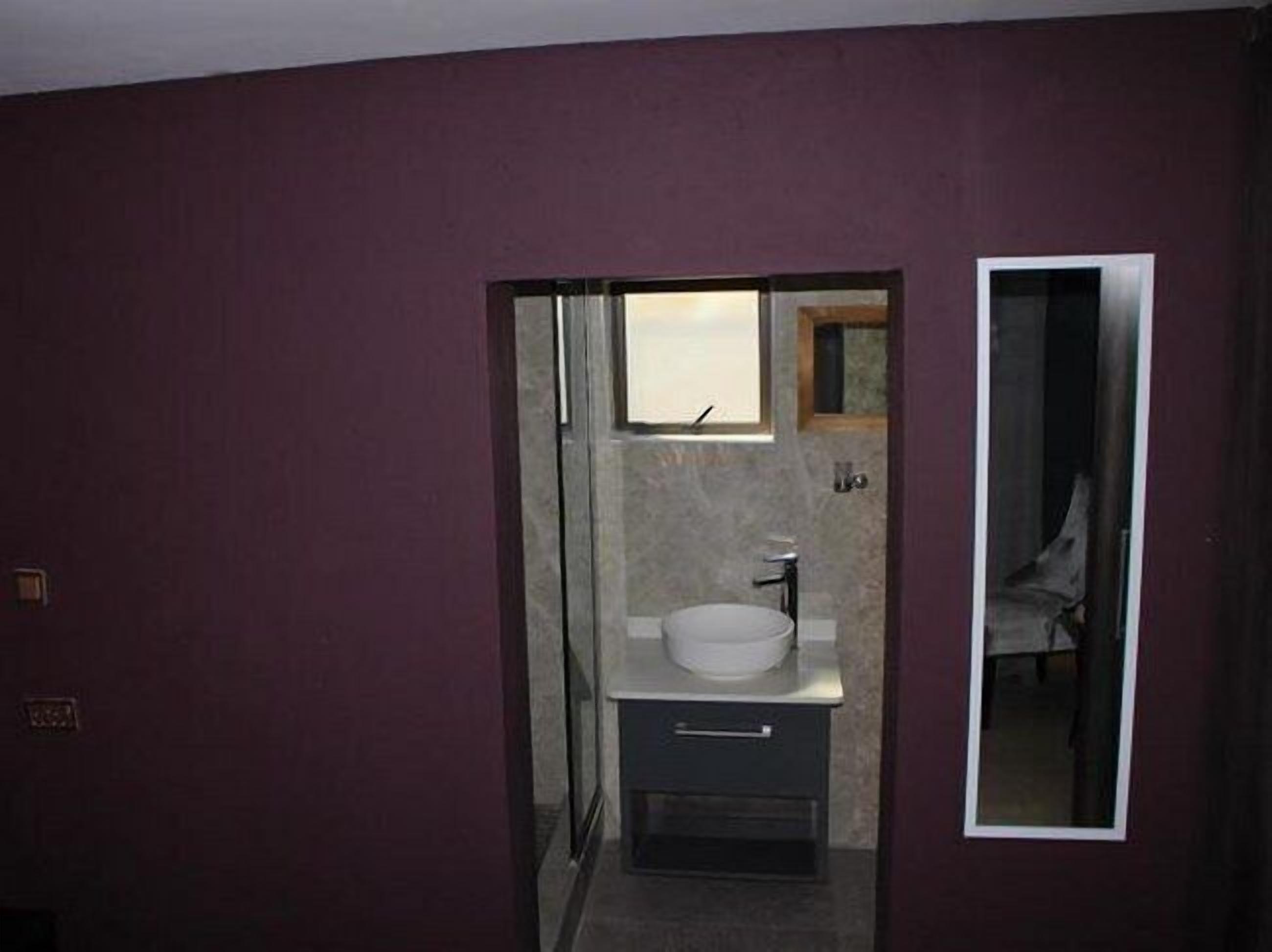 A bathroom with a white sink, a mirror, and a small window.