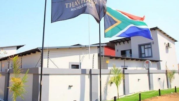 A building with a flag bearing the Thavha Boutique Hotel logo and the South African flag.