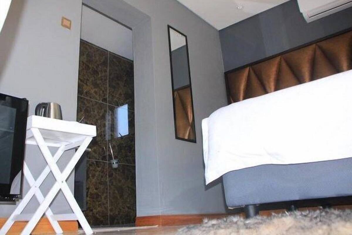 A hotel room with a bed, a TV, a small table, and a shower area.