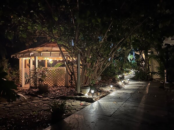 Relax in this serene garden gazebo surrounded by lush greenery and a meandering stone path.