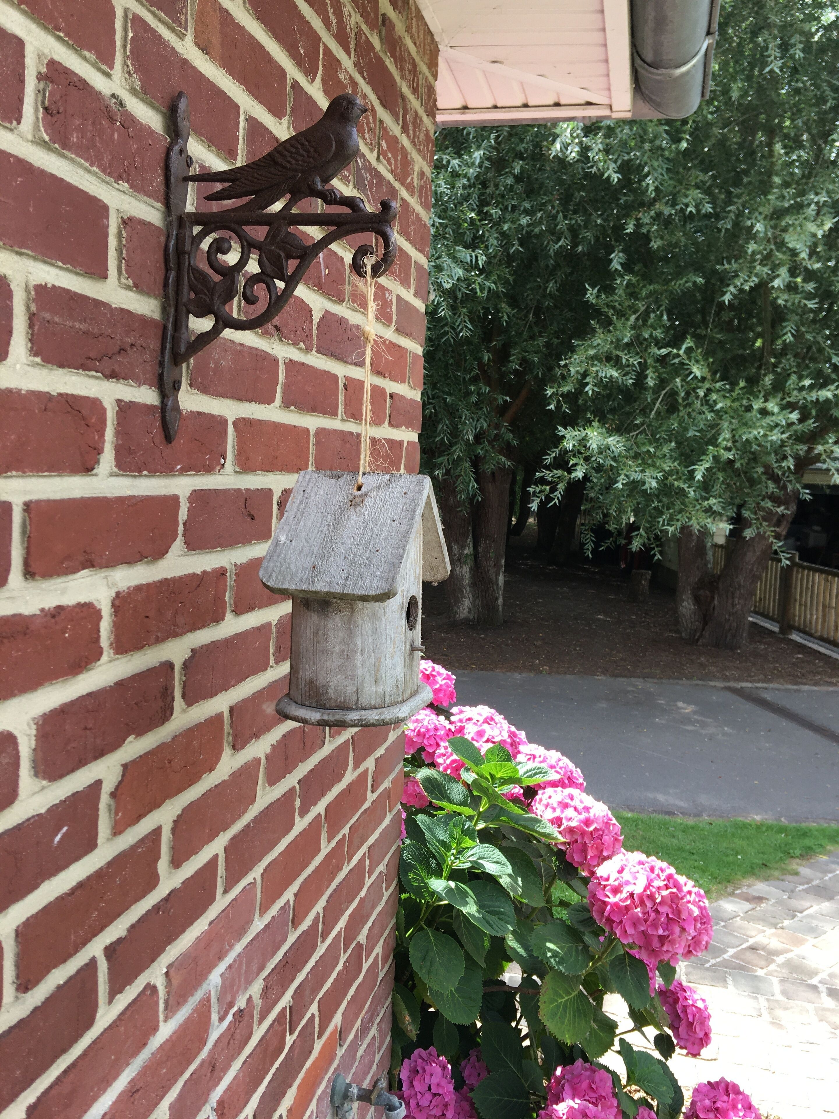 A brick wall with a birdhouse and a bird feeder mounted on it.