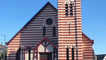 Een kerk met een gevel in rode en witte strepen, een opvallende klokkentoren en een rode deur.
