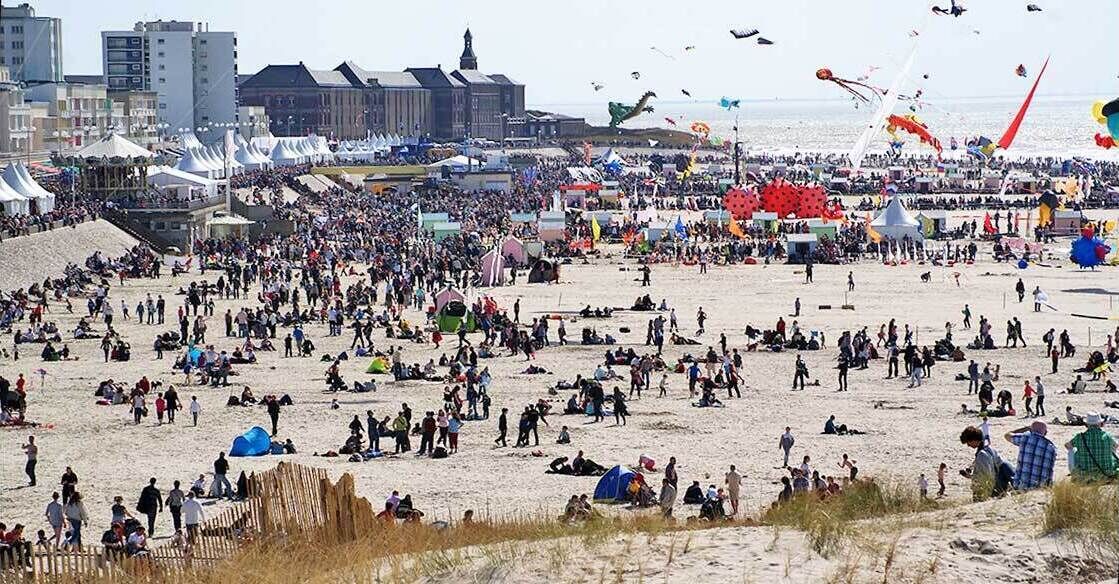 Een druk strand met tenten en mensen.