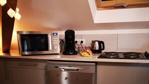 A modern kitchen with a microwave, coffee maker, and toaster on the counter, a dishwasher, and a black rug with French text.