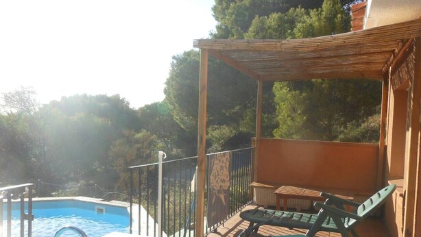Zona junto a la piscina con una terraza de madera, una mesa y una silla, y vista a una piscina.