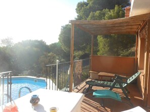 Un espace aménagé au bord de la piscine, avec une terrasse en bois, une table et une chaise, et une vue sur la piscine.