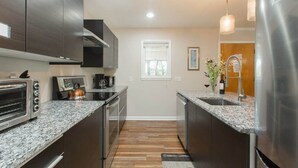 Une cuisine moderne avec des meubles sombres, des plans de travail en granit, des appareils électroménagers en acier inoxydable et une fenêtre offrant une belle vue.