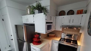 A compact kitchen with white cabinets, a stainless steel refrigerator, a microwave, and an oven.