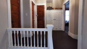 A hallway with white railings, wooden doors, and a white cabinet with baskets.