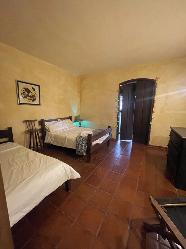 Una habitación pequeña y con poca luz, con cama, una silla, un escritorio y un armario.