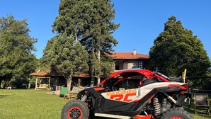 A red and black off-road vehicle parked on a grassy lawn. - Pousada Refúgio Dinamarca (Mairipora)