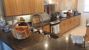 Una cocina con armarios de madera, encimera de granito, pileta de acero inoxidable y tabla de cortar de madera.