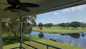 Una habitación con un amplio ventanal que da a un estanque y un campo de golf.