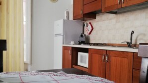 Une cuisine avec des meubles de rangement en bois, un réfrigérateur blanc, un four à micro-ondes et un évier.