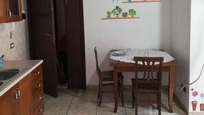 Une cuisine de taille réduite comprenant une table à manger, des chaises et un meuble de rangement.