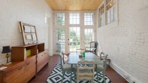 A dining area with a wooden ceiling, white brick walls, and a large window.