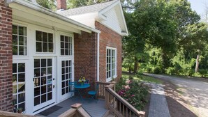 A brick house with a deck, a table with chairs, and a garden.