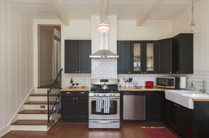 Kitchen features stainless steel appliances, a wooden countertop, and a hanging light fixture above the stove.