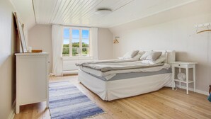 A bedroom with a bed, a dresser, a bedside table, a hanging light, and a window with a view of greenery. - Awesome home in Långserud with WiFi (Långserud)