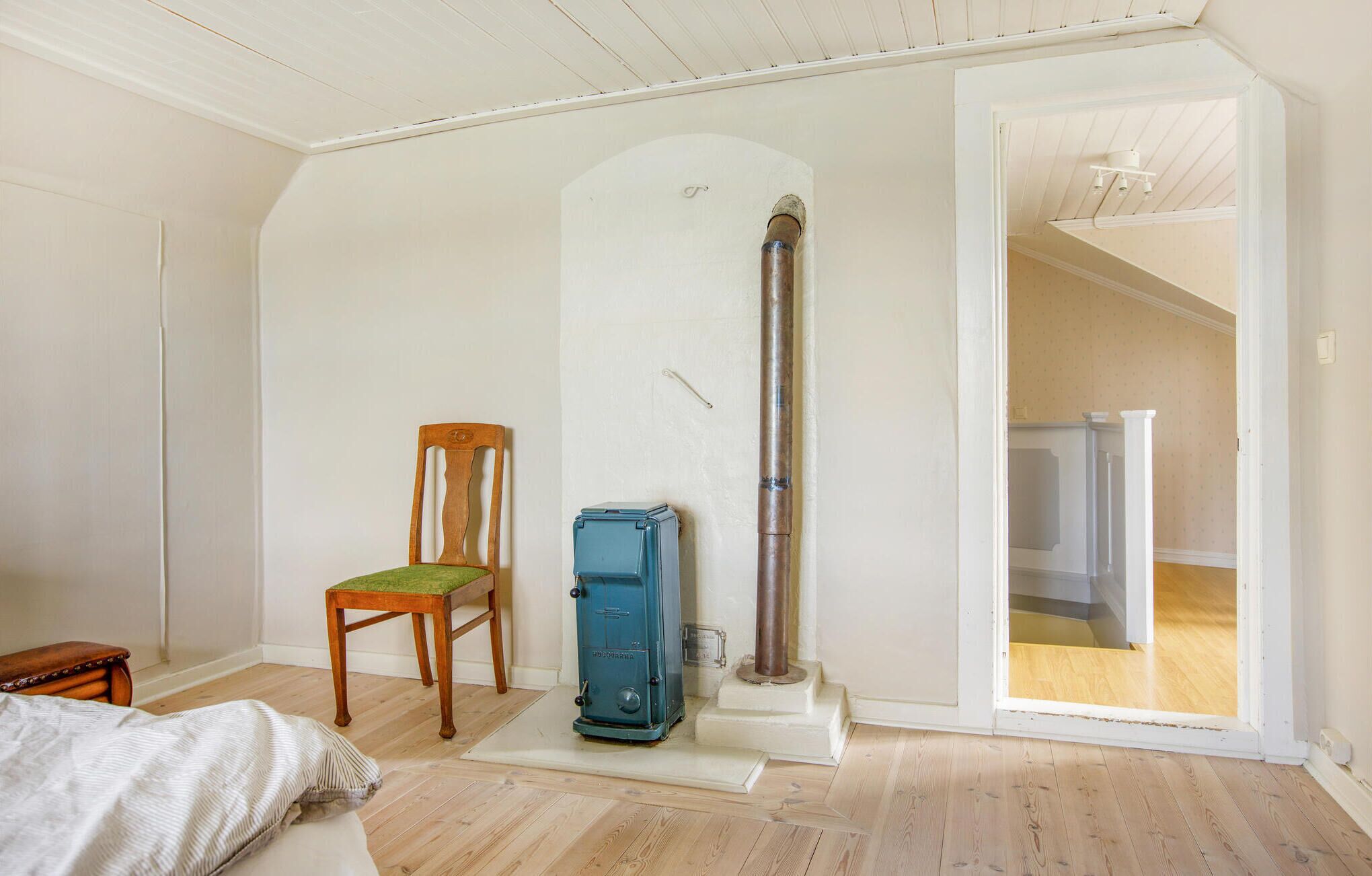 A room with a wooden chair, a blue heater, and a wooden floor.