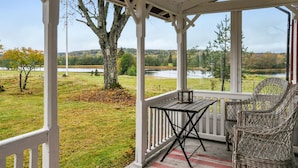 A covered porch with a table and chairs, overlooking a lake and forested area. - Awesome home in Långserud with WiFi (Långserud)