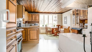 A kitchen with wooden cabinets, a dining area with chairs, and a large window providing natural light. - Awesome home in Långserud with WiFi (Långserud)
