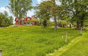 Situated on a lush hillside, this traditional house offers a peaceful retreat surrounded by mature trees and a well-manicured lawn.