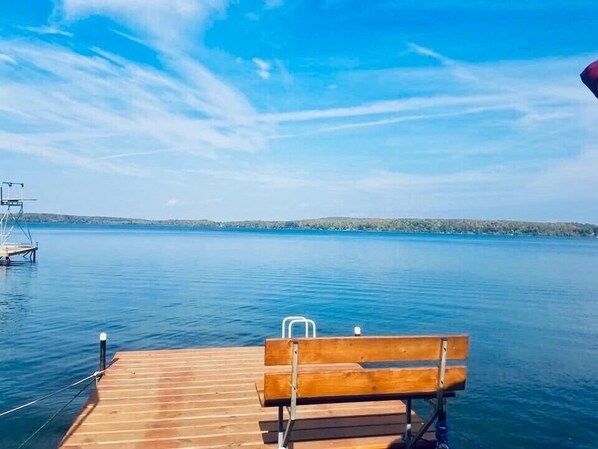Un muelle de madera que se adentra en aguas tranquilas, con un banco en primer plano.