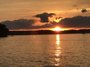 Un atardecer sobre un lago tranquilo con un bote en el agua.