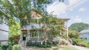 A two-story house with a front porch, a staircase leading to the second floor, and a well-maintained garden. - 3 BR Charleston Style Home- 3 levels with garage (Atlanta)