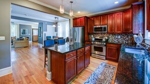 A spacious kitchen with wooden cabinets, a granite countertop, stainless steel appliances, and a large island. - 3 BR Charleston Style Home- 3 levels with garage (Atlanta)