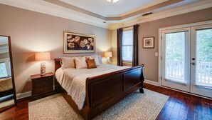 A bedroom with a large bed, a nightstand, a lamp, a framed artwork, and a sliding glass door to the outside. - 3 BR Charleston Style Home- 3 levels with garage (Atlanta)