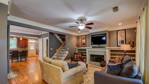 A spacious living room with a fireplace, a television, and a staircase leading to another level. - 3 BR Charleston Style Home- 3 levels with garage (Atlanta)