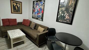 Un salon moderne avec un canapé d’angle, une table basse et un coin repas comprenant une table ronde et des chaises.