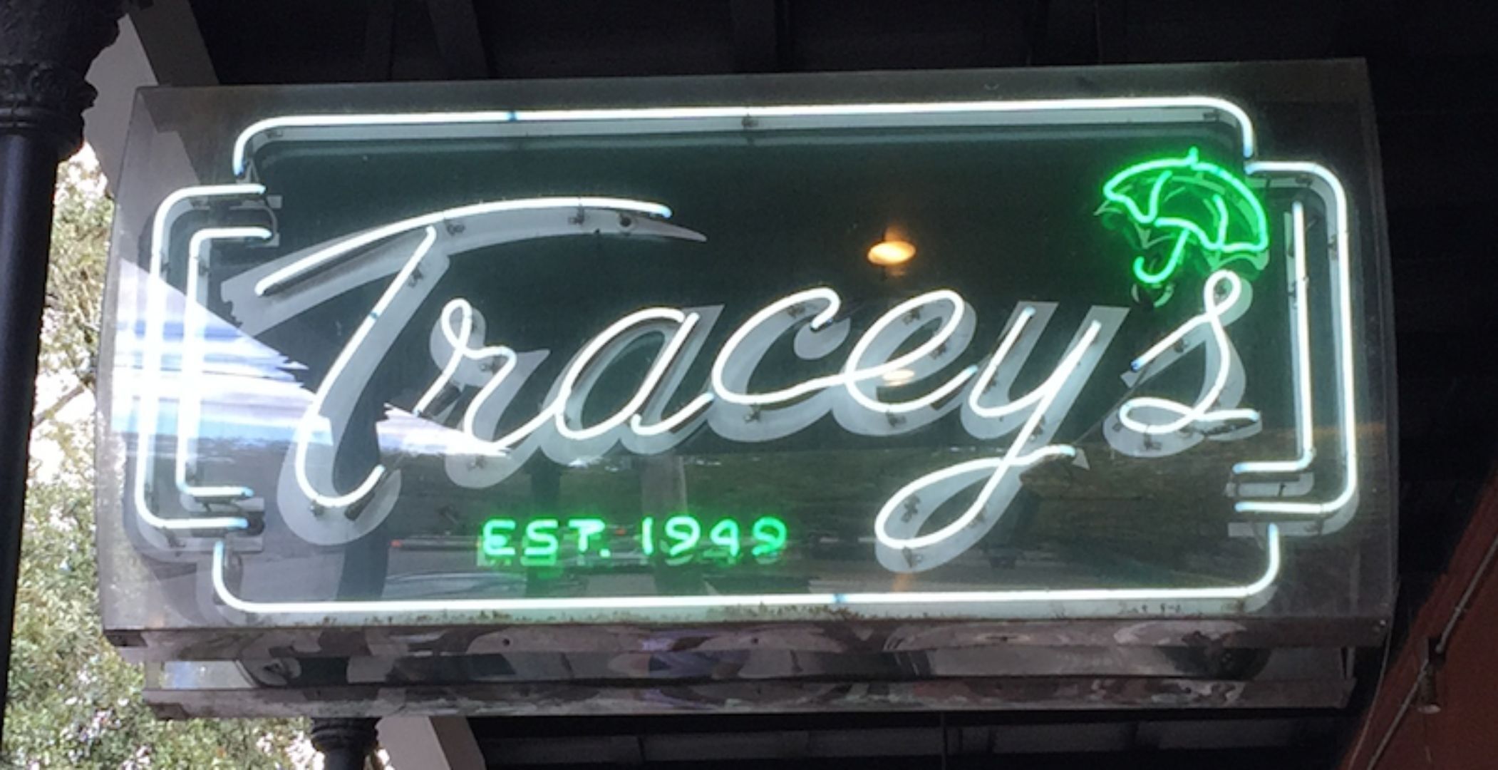 A neon sign for 'Tracey's' with the establishment year 'EST. 1999'.