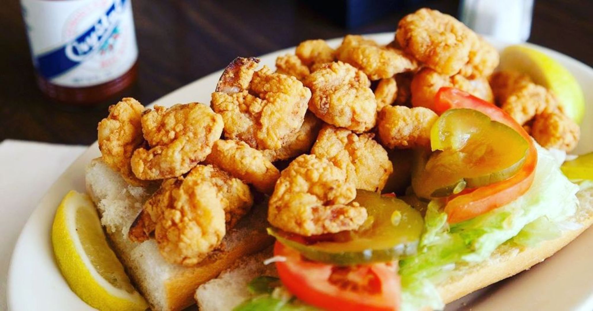Une assiette de poulet frit, accompagnée de quartiers de citron et de cornichons, le tout servi dans un pain.