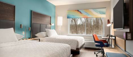 A hotel room with two beds, a desk, a chair, and a TV.