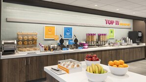 Zona de desayuno tipo bufé con diversas opciones de comida como rosquillas, gofres y huevos.