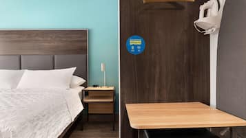 Une chambre à coucher avec un lit, une table de chevet et un petit bureau avec une chaise.